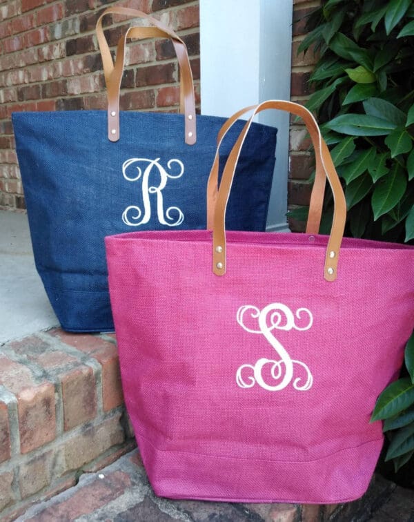 Two bags with a monogram on them sitting next to each other.