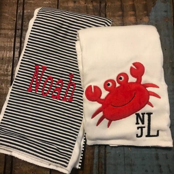 A pair of towels with the name noah and an image of a crab.