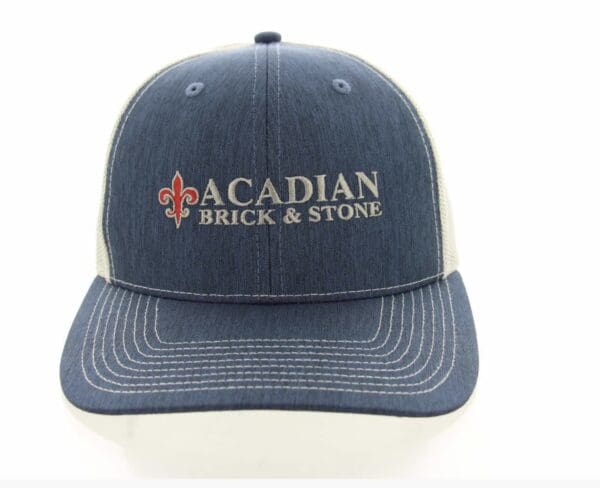 A blue and white hat with the words acadian brick & stone on it.