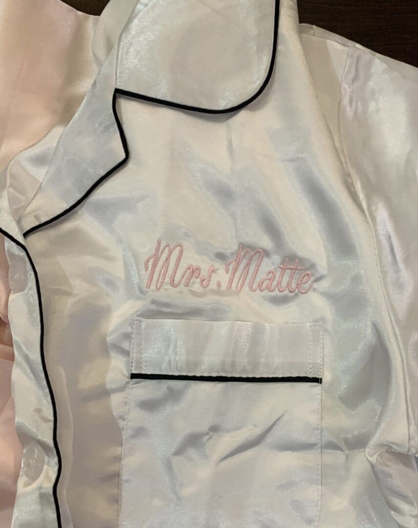 A white satin jacket with pink writing on it.