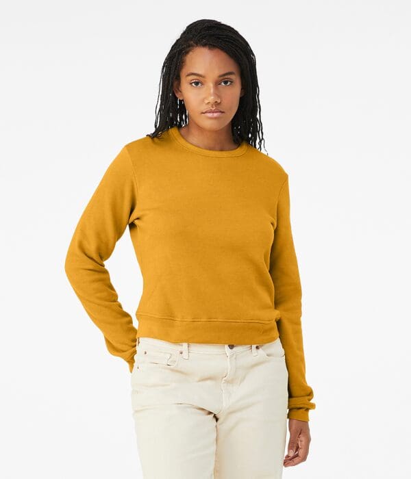 A woman wearing a yellow sweater and white pants.