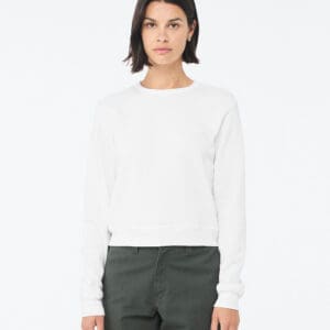 A woman wearing white sweater and green pants.