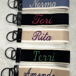 A group of six key chains with the names of five different people.