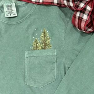 Green shirt with embroidered trees in pocket.